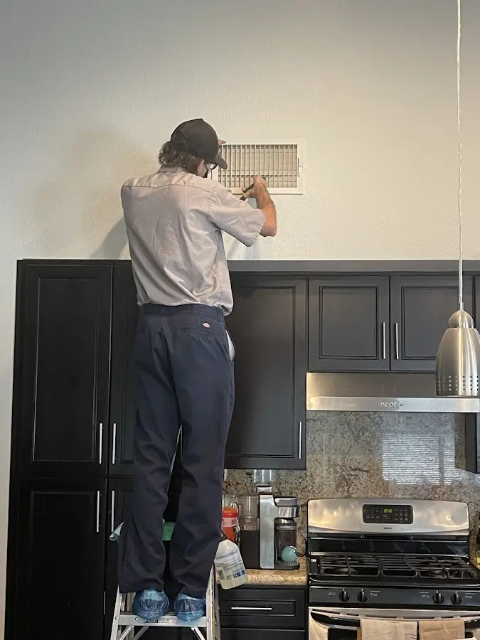 Technician inspecting an air vent during HVAC service in Riverdale